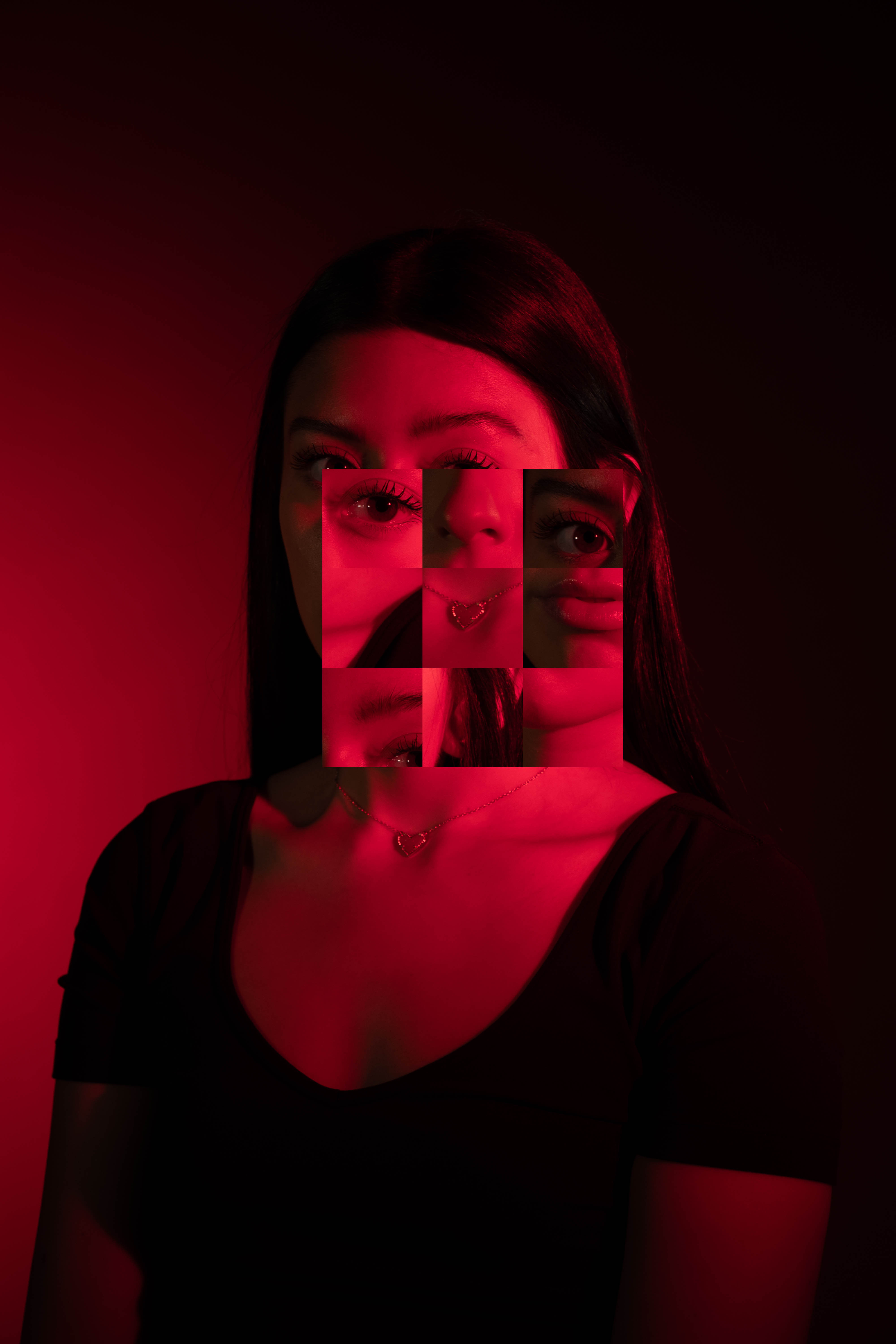 studio photograph of a girl with dark hair, wearing a black shirt, with red light highlighting her face and the background; face is replaced with a grid of nine squares