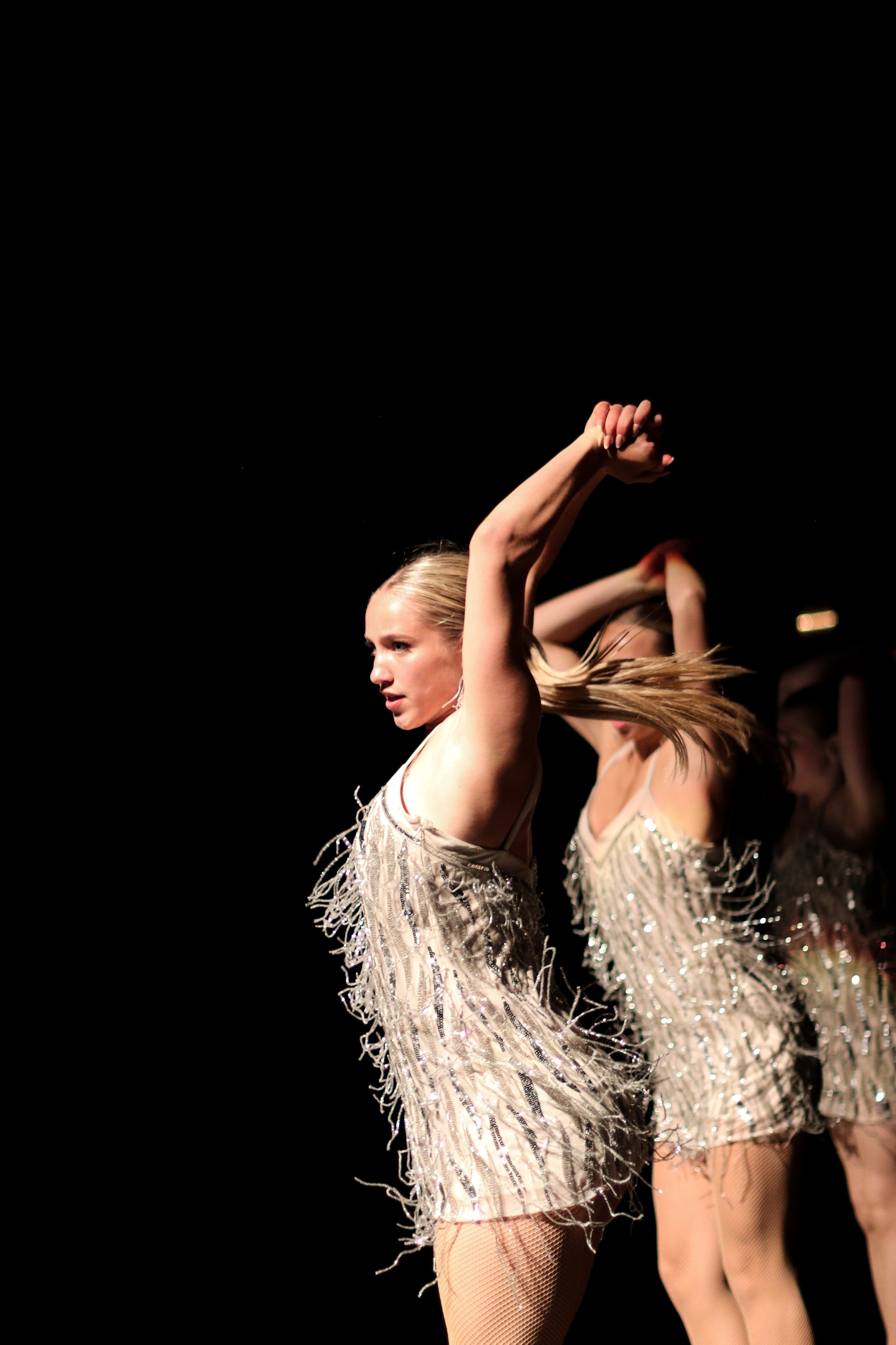 girl with blonde hair in a sparkly silver dress dancing