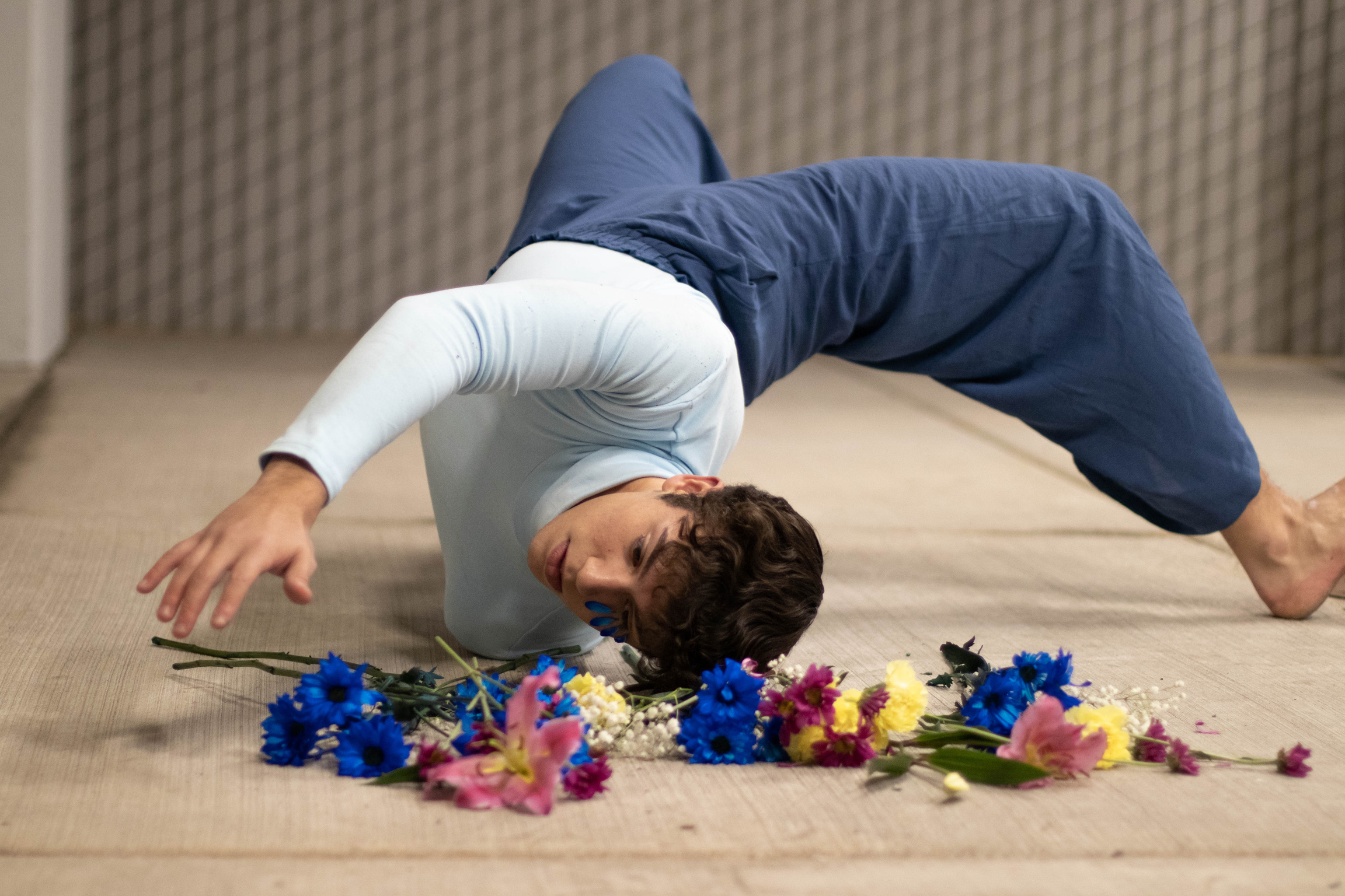 editorial photo of a boy with brown hair lying on concrete in a bed of flowers